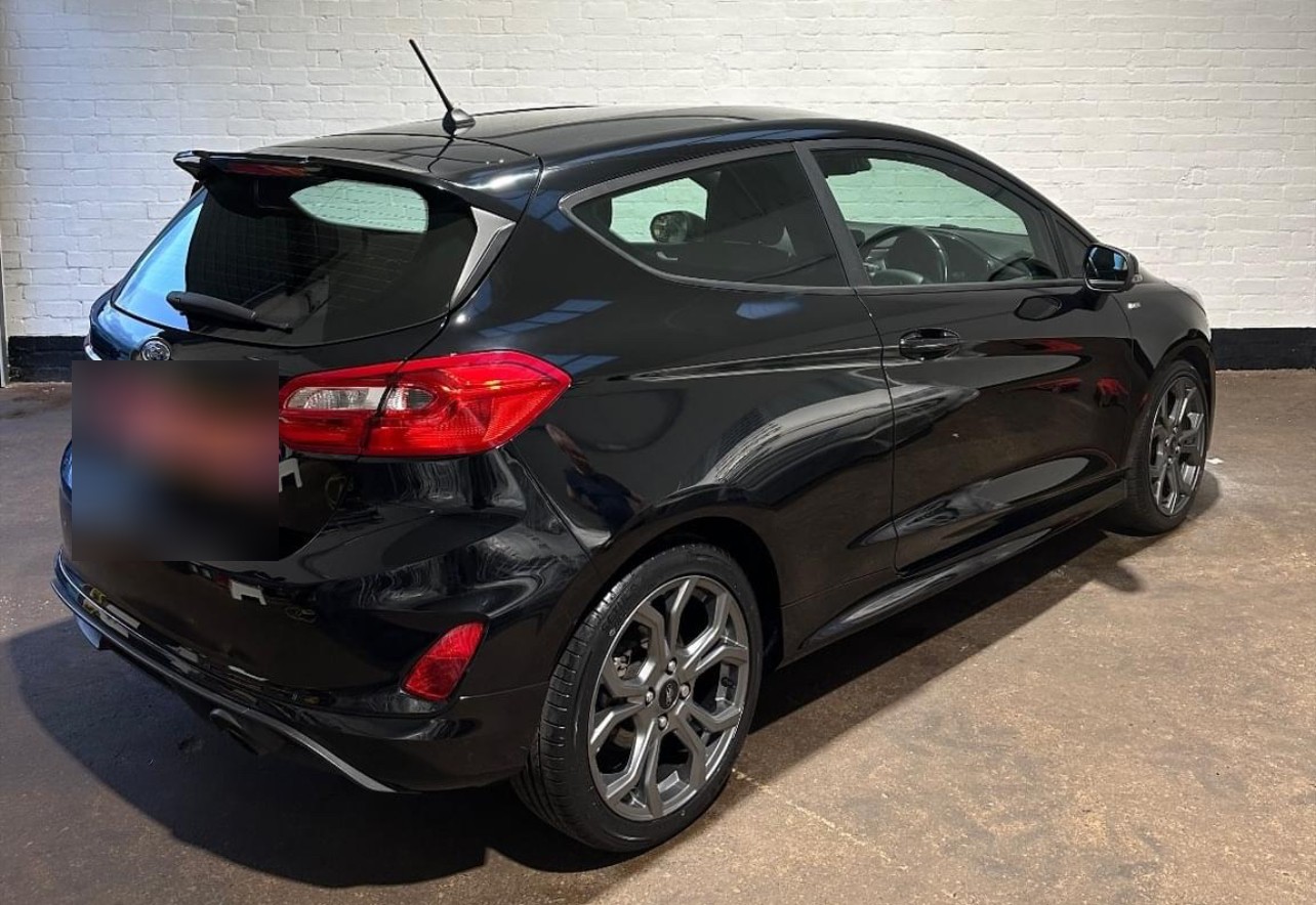 A black Ford Fiesta parked against a white brick wall